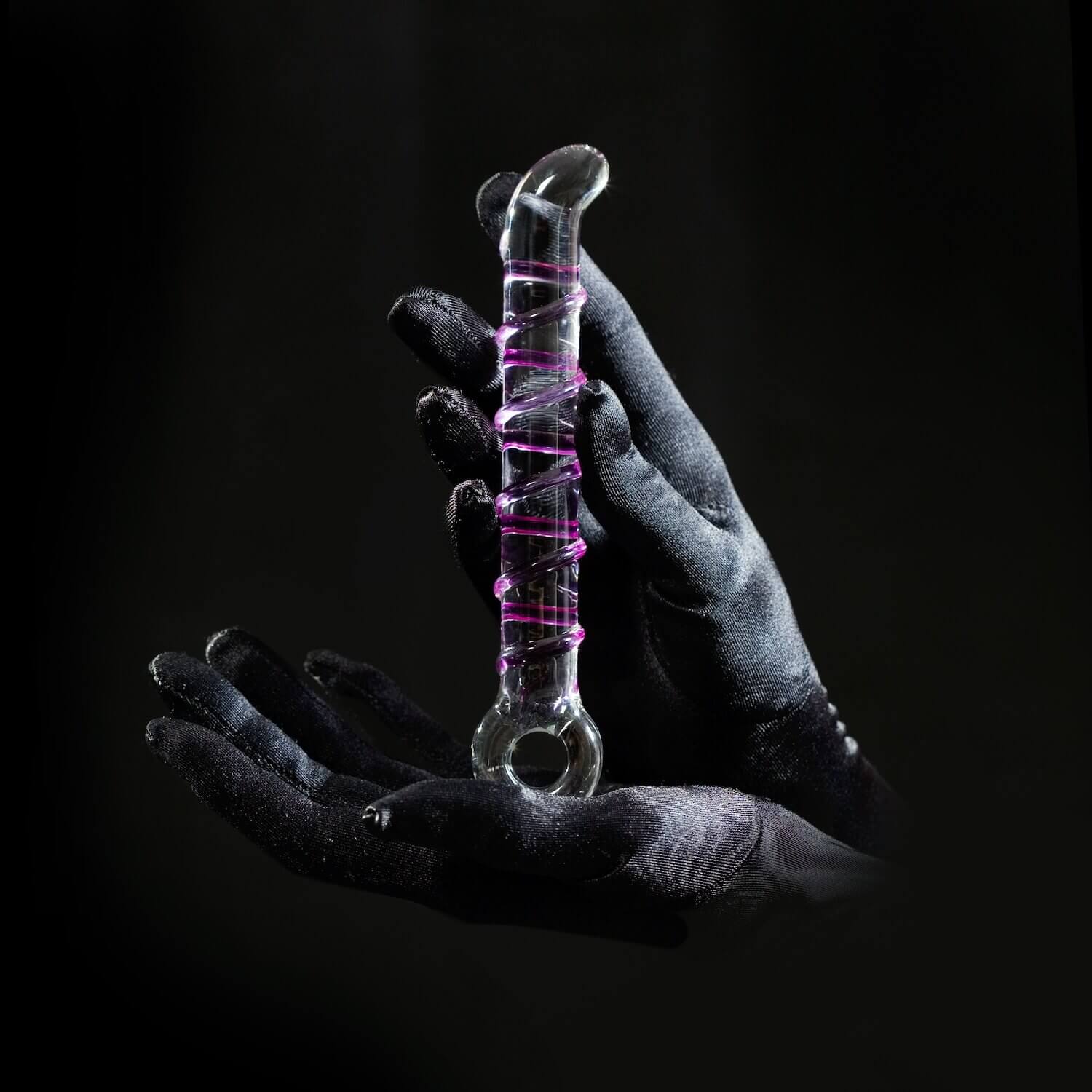 Hands holding a clear glass anal plug.