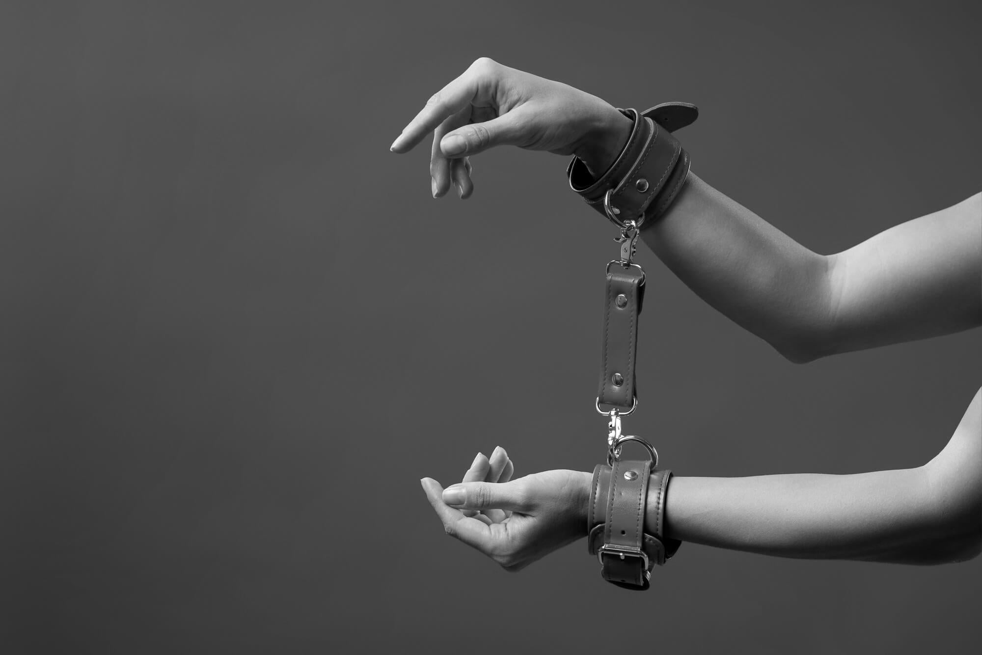 Woman wearing BDSM restraints and sexual handcuffs in leather.