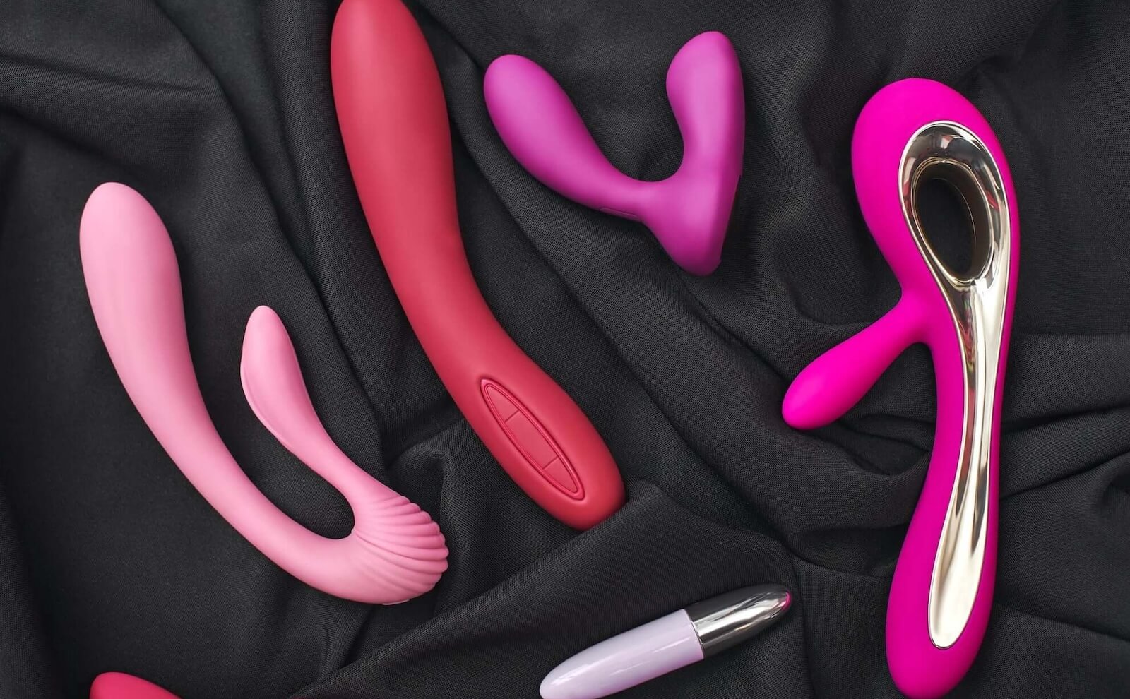 Vibrating realistic dildos on a black velvet sheet.