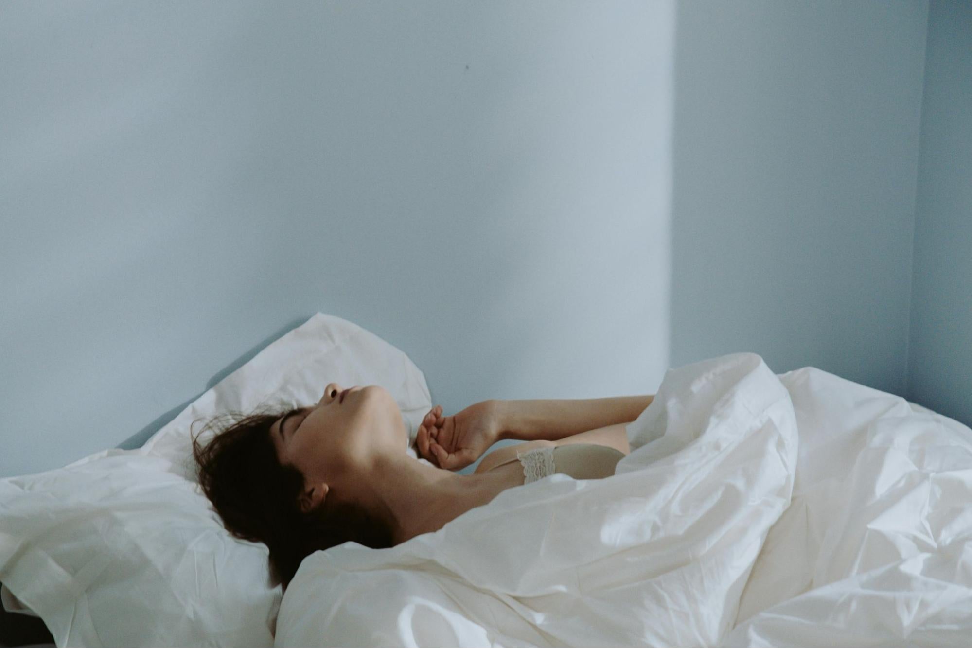 Woman in bed exploring one type of vibrator. 