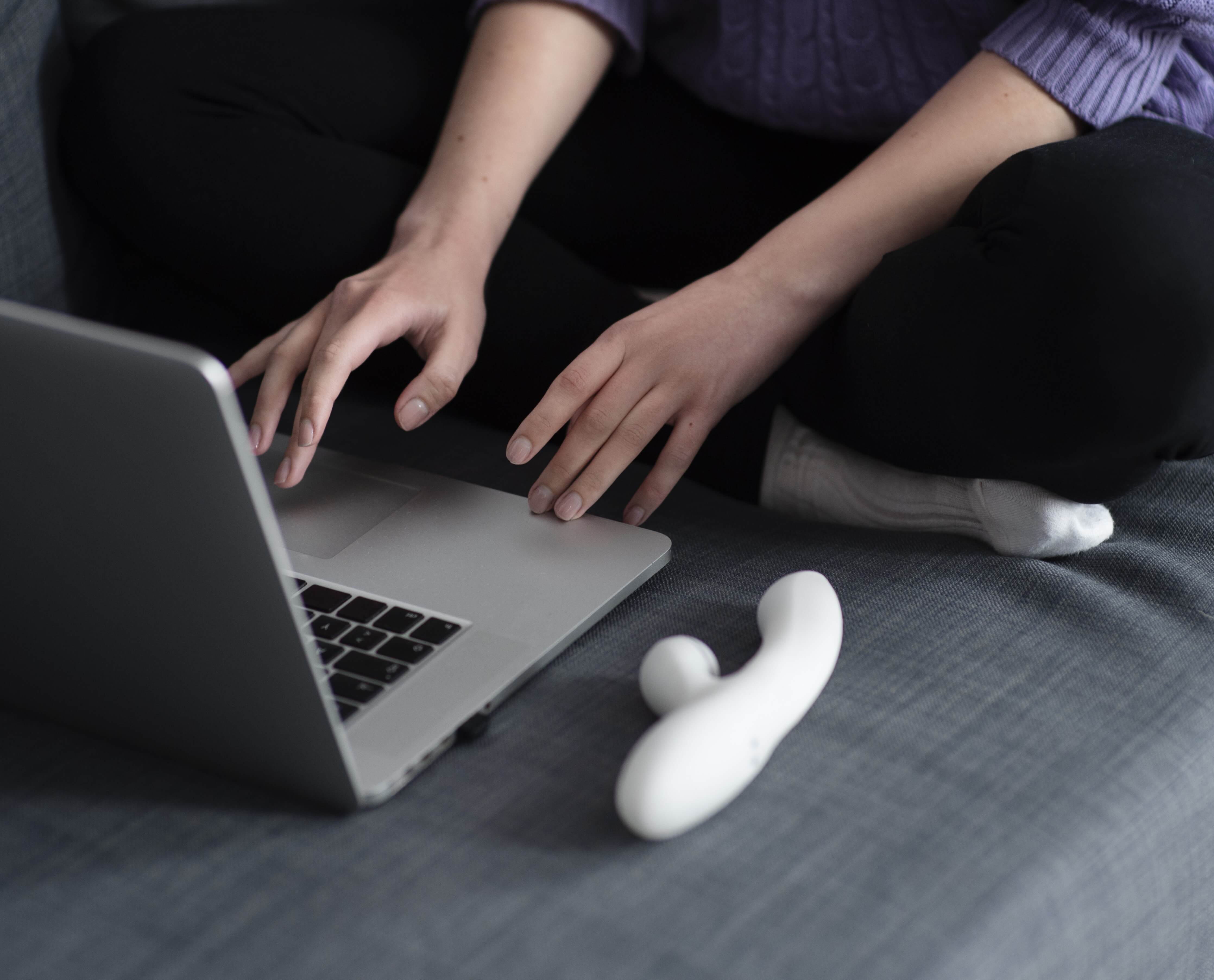 Woman researching confident pleasure techniques with vibrator nearby.
