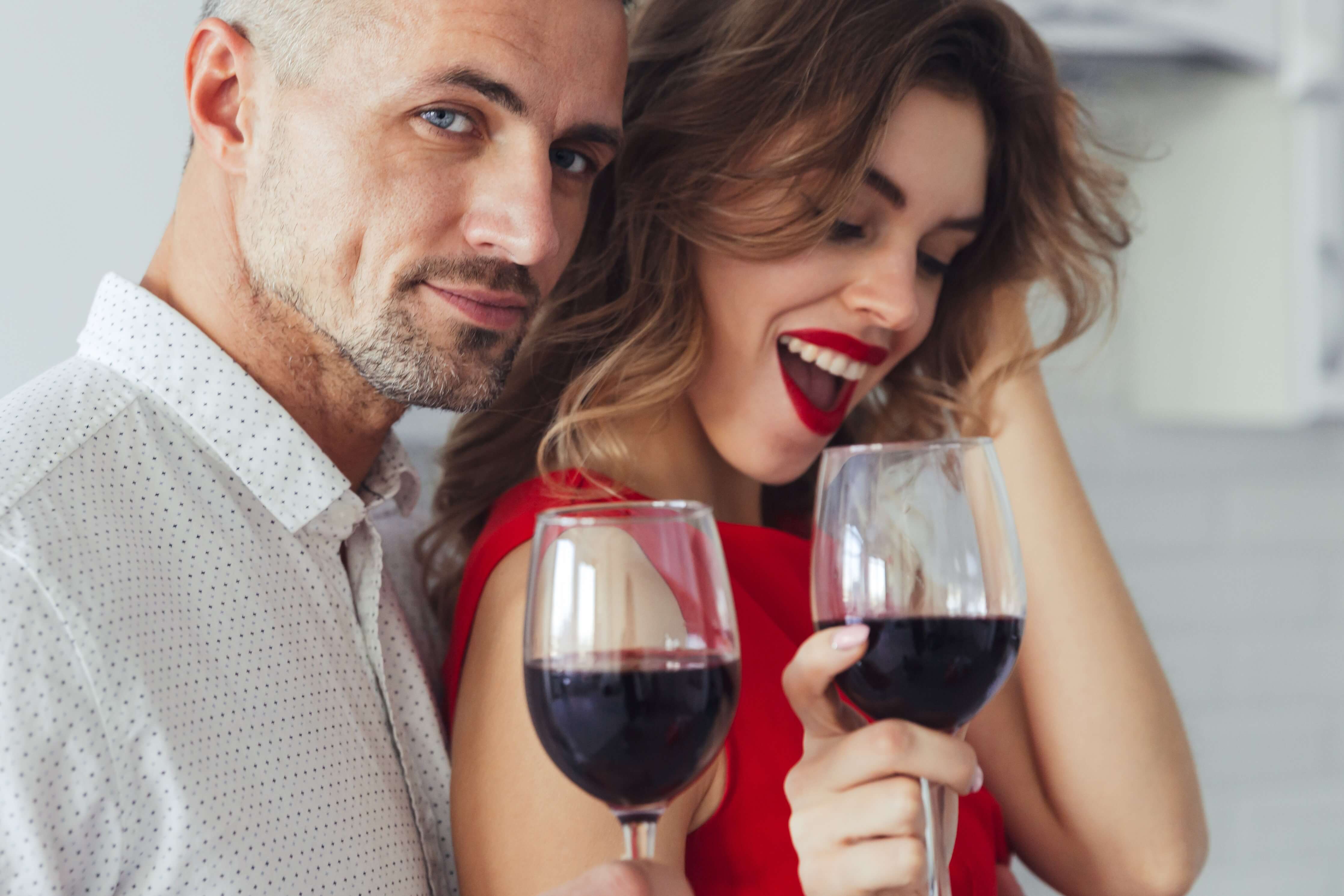 Couple enjoying a romantic evening with red wine while discussing safe sex practices and condom use for glass dildos.