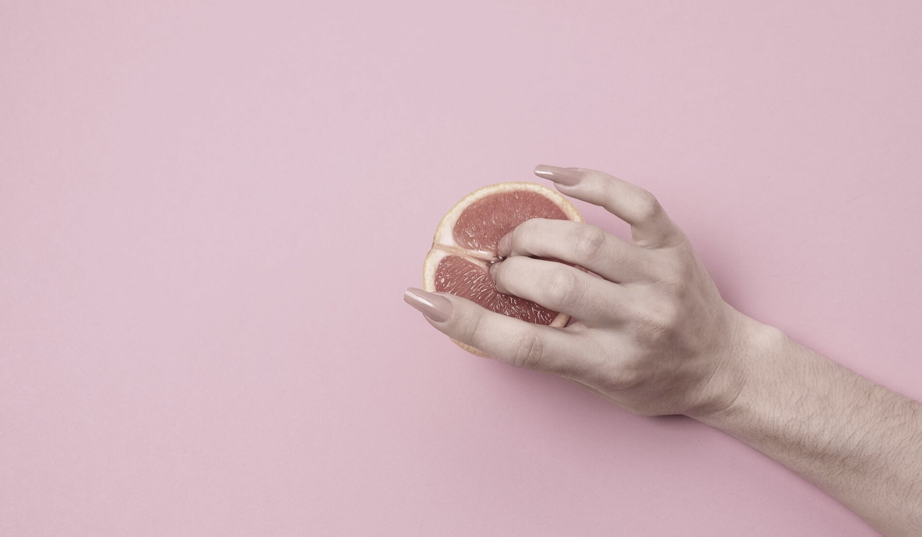 Woman hand and fingers showing the motion of clit toy and clit stimulator motion on the clitoris using an orange.