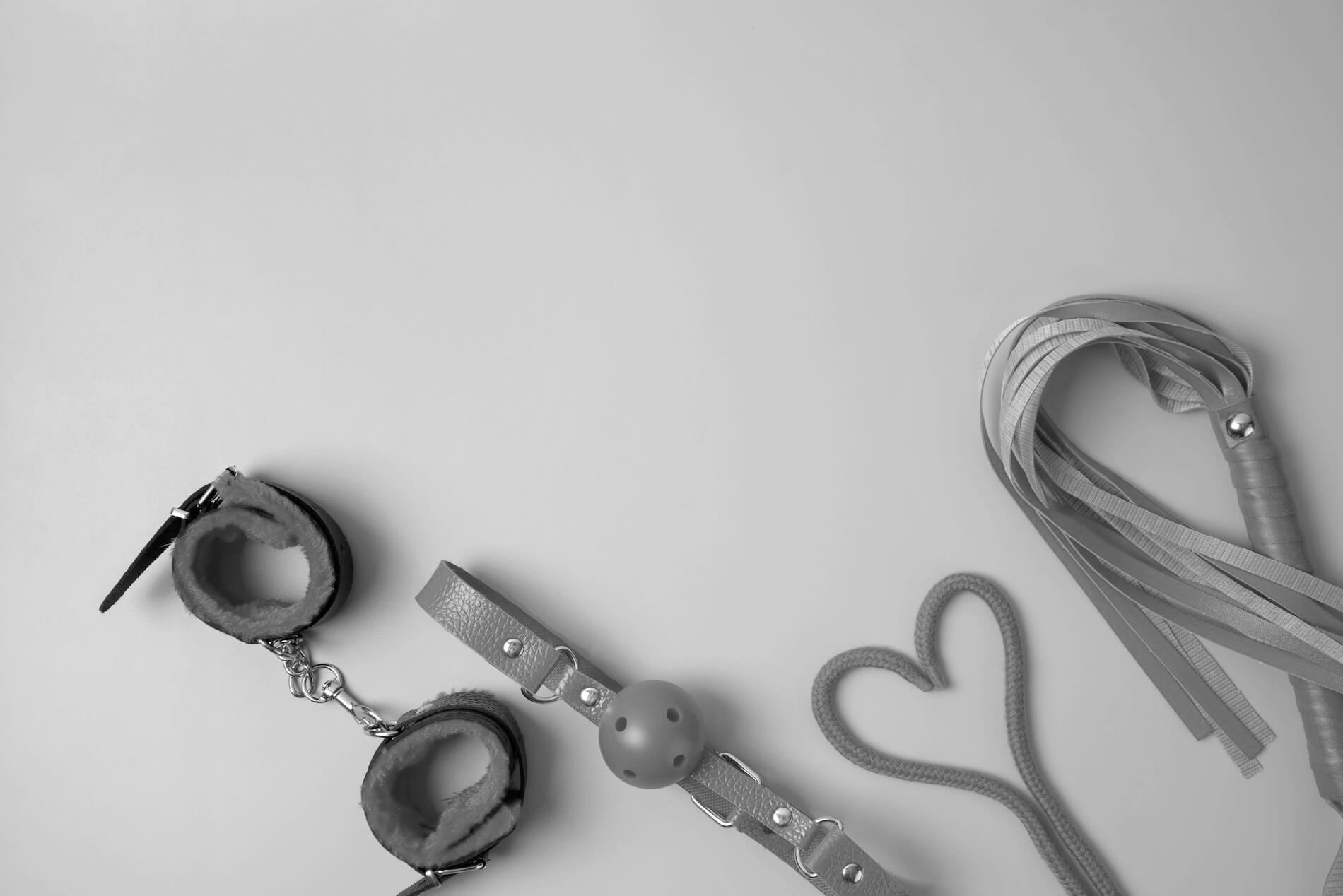 Leather handcuffs and leather bondage gear and BDSM toys on a light background