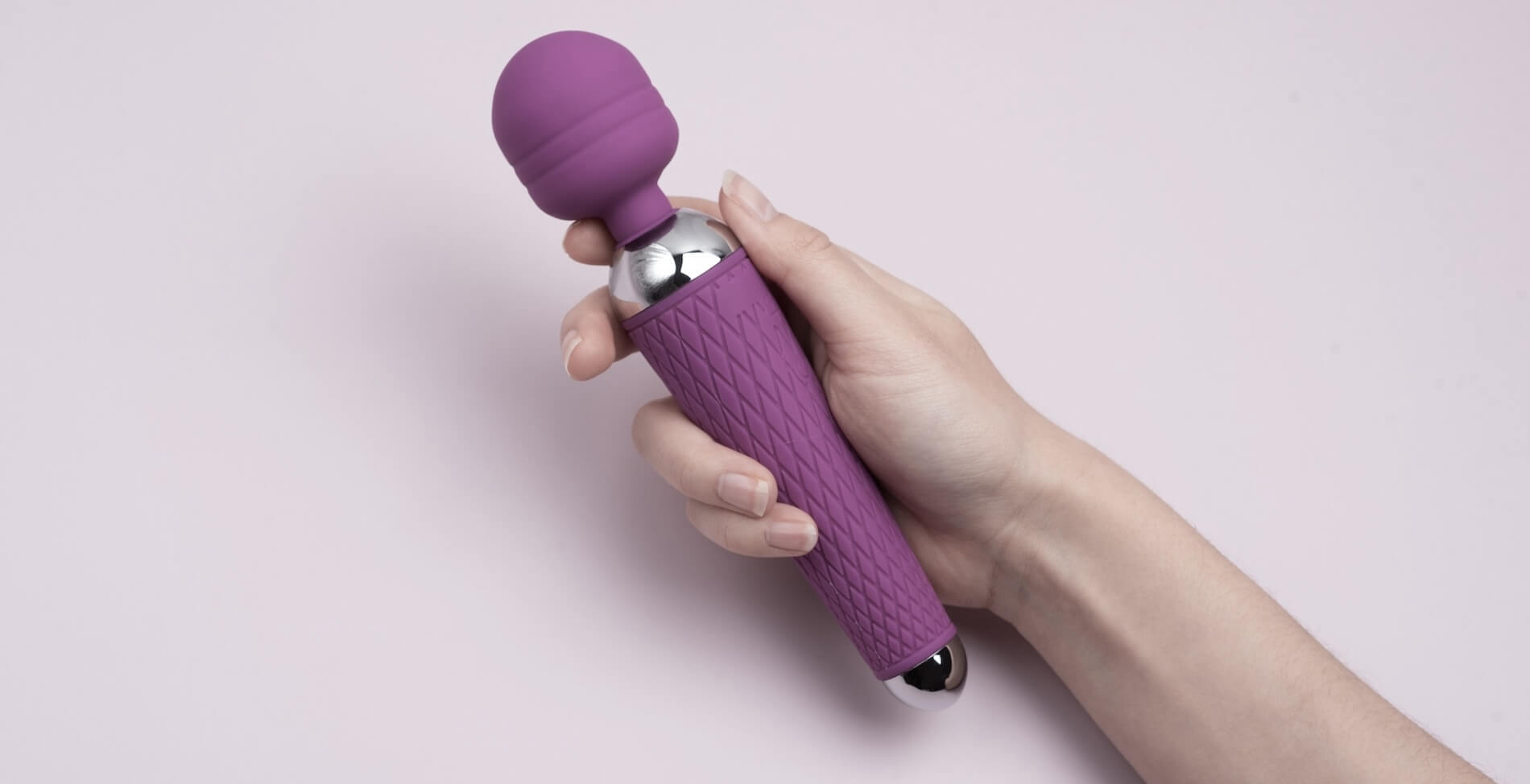 Woman hand holding a pink vibrating wand or massage wand. 