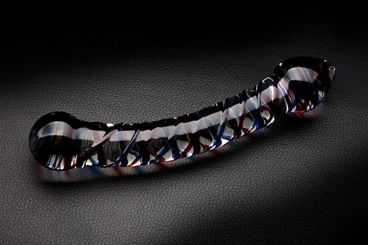 Glass dildo with red and blue stripes on a black leather background
