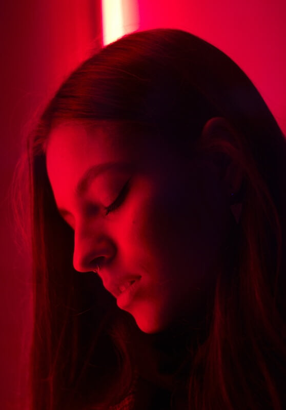 Woman in dramatic red and green lighting with eyes closed