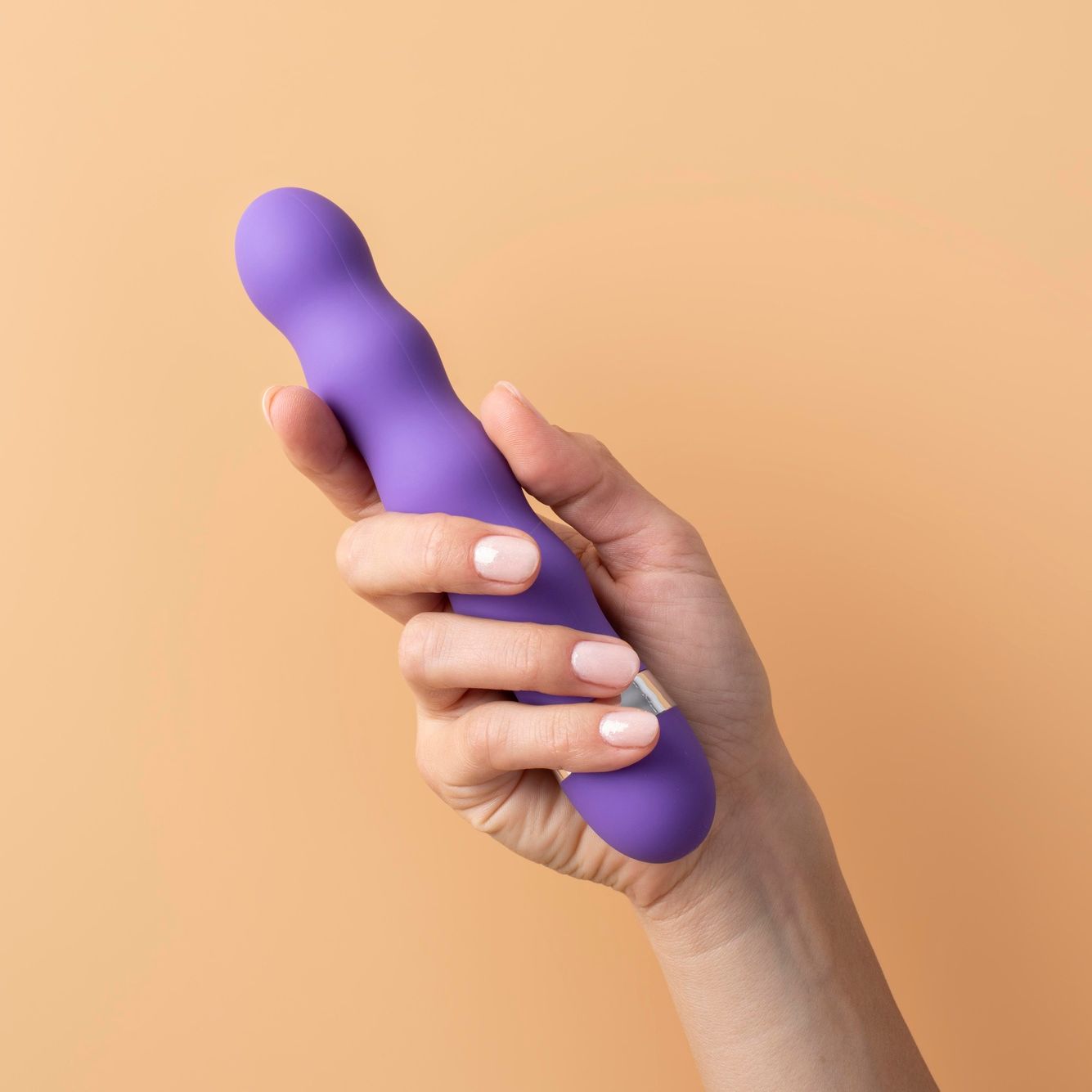 Purple vibrating Dildo in a woman's hand with pink polished classy nails