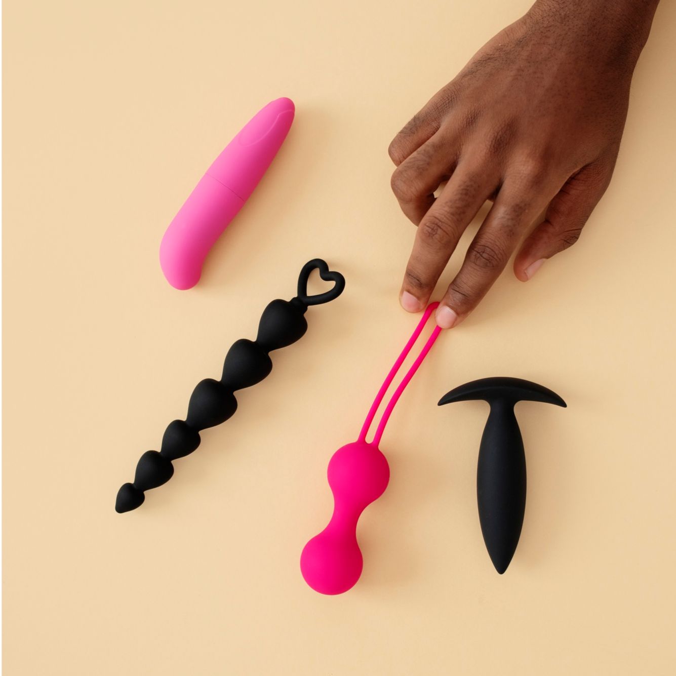 Black anal beads sex toy with black butt plug bullet vibrator and a black woman hand holding kegel balls exerciser